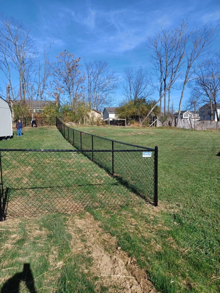A newly installed black chain link fence enclosing a large backyard area by A Freedom Fence in Martinsburg, WV.