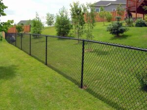 A black chain link fence installed on a sloped grassy area by Ace Fence Company in Fort Lauderdale, FL.