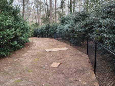 A newly installed black chain-link fence along a wooded property line by Almaraz & Sons LLC in Macon, GA.