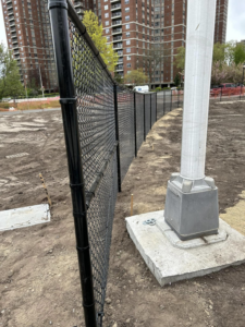 A newly installed black chain-link fence in an urban area by Building Fences in Westchester NY.