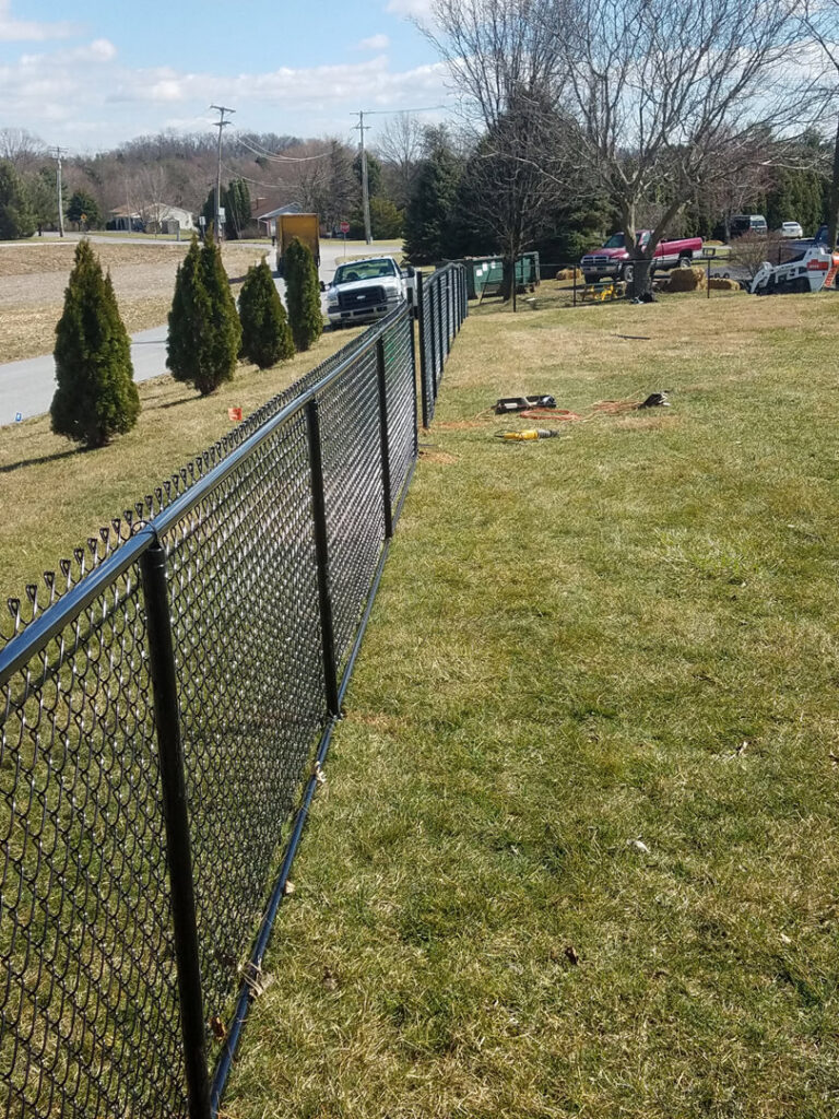 A newly installed black chain-link fence along a property line by DZS Fencing, LLC in Red Lion, PA.