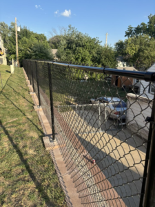 A long black chain-link fence installed on a retaining wall by Schulze Enterprises in Bellevue, NE.