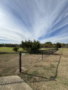 A black chain-link fence installed in an open field by TC Fencing LLC in Tuscaloosa, AL.