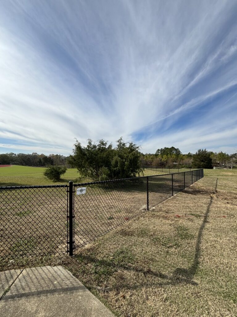 A black chain-link fence installed in an open field by TC Fencing LLC in Tuscaloosa, AL.
