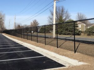 A black chain-link fence installed along a commercial parking lot by Roy & Son Fencing in Lee's Summit, MO.