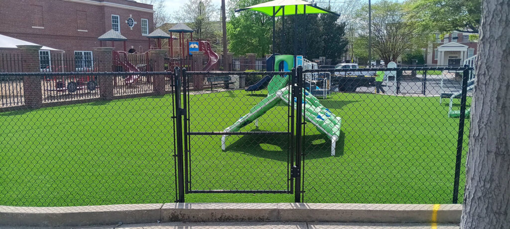A black chain-link fence enclosing a playground area by Creative Fence Designs in Columbus, GA.