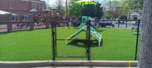 A black chain-link fence enclosing a playground area by Creative Fence Designs in Columbus, GA.