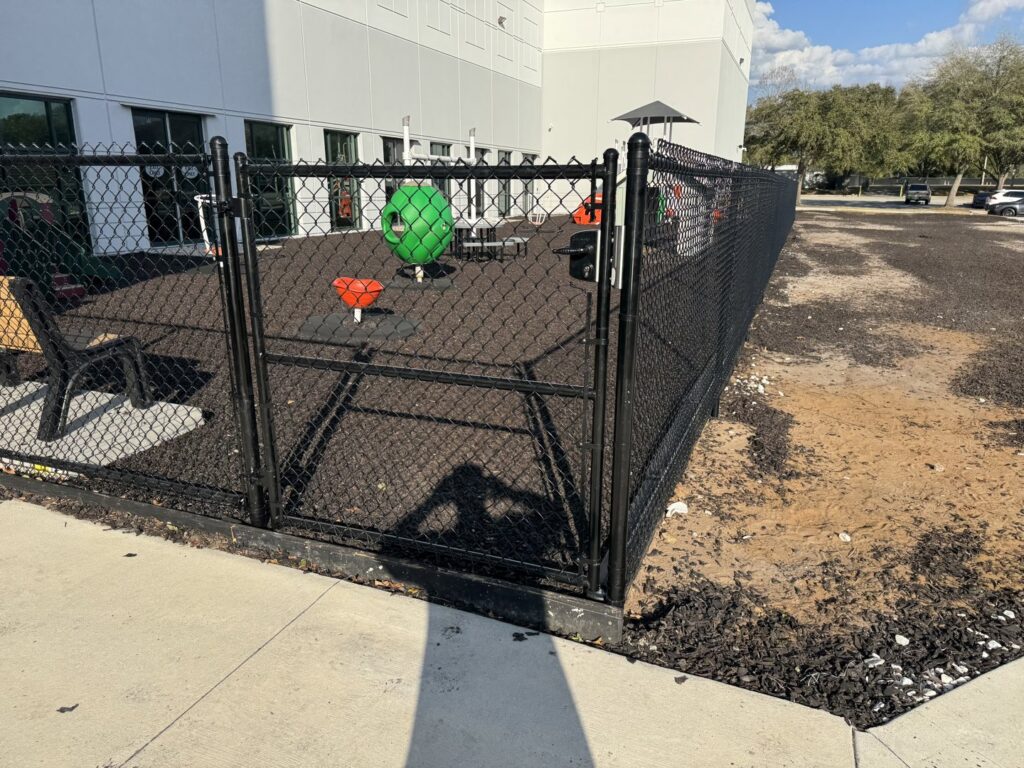 A durable black chain link fence enclosing a playground area, installed by Fence Nation LLC in Jacksonville, FL.