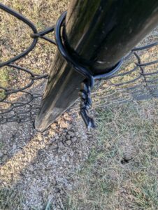 A close-up view of a black chain link fence post and wire installed by Complete Fence, LLC in West Chicago, IL