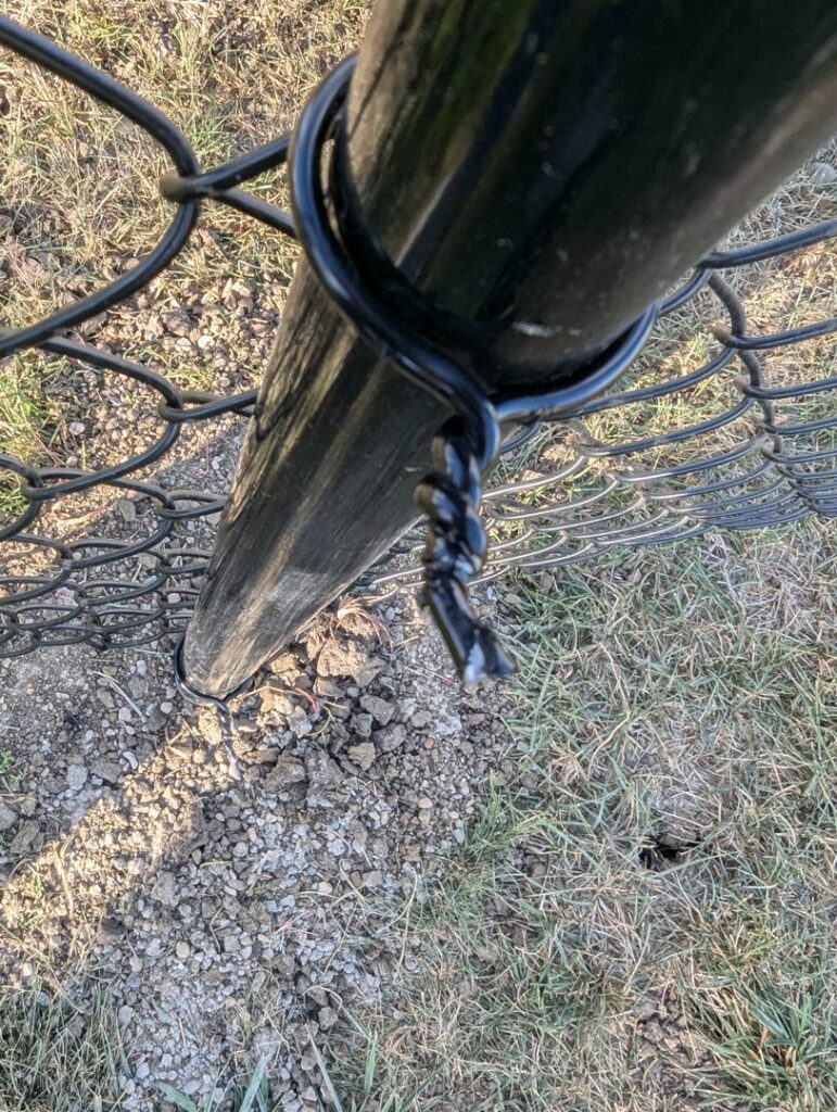 A close-up view of a black chain link fence post and wire installed by Complete Fence, LLC in West Chicago, IL