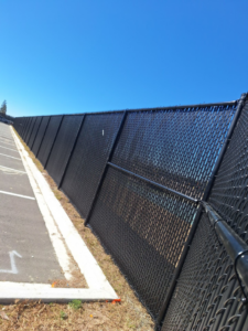 A black chain-link fence with privacy slats running alongside a parking lot, installed by First Fence of Georgia in Kennesaw, GA.