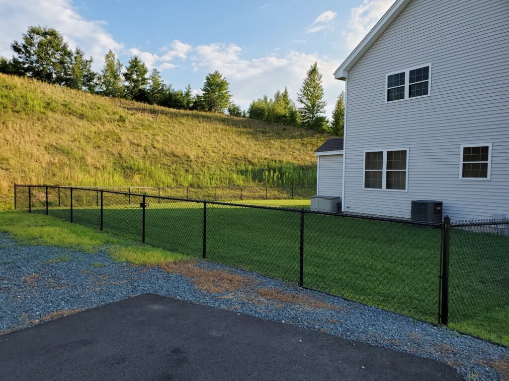 A black chain-link fence installed around a residential property by MH Fence in Weare, NH.