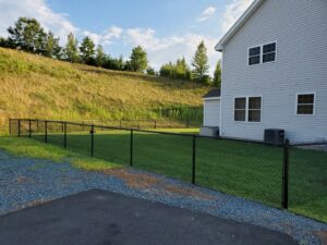 A black chain-link fence installed around a residential property by MH Fence in Weare, NH.