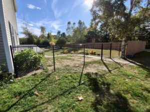 A black chain-link fence installed around a residential yard, providing security by Dirigo Fence Company in Augusta, ME.