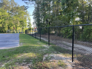 A long black chain-link fence installed alongside a road or parking lot by Alabama Fence & Rail LLC in Birmingham, AL.