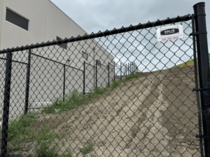 Black chain-link fence installed on a sloped terrain next to a building by Solid Fence Co. in Sioux Falls, SD.