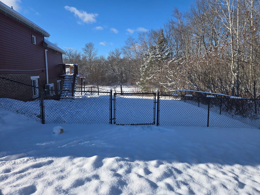 A long black chain link fence enclosing a snowy backyard, installed by Dore's Fence Company in Greenbush, ME.
