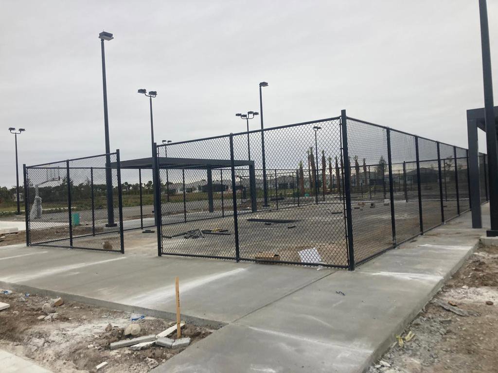 A black chain-link fence enclosing an outdoor sports court, installed by Allende J. Service Corp in Miami, FL.