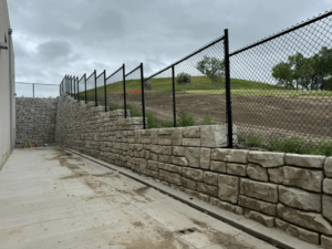 Black chain-link fence installed on top of a stone retaining wall by Solid Fence Co. in Sioux Falls, SD.