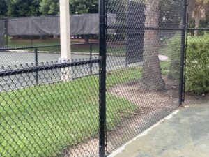 A section of black chain-link fence surrounding a tennis court, installed by Allende J. Service Corp in Miami, FL.