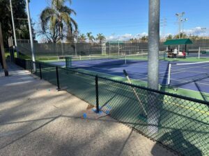 A black chain-link fence installed around a tennis court by Superior Fence & Rail, a fencing contractor in San Jose, CA.