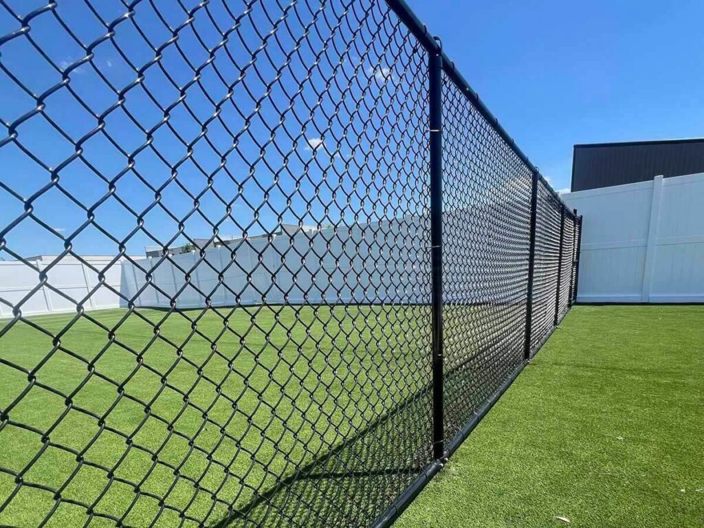 A black chain-link fence enclosing a green turf area, installed by Golden Eagle Fencing in Tampa, FL
