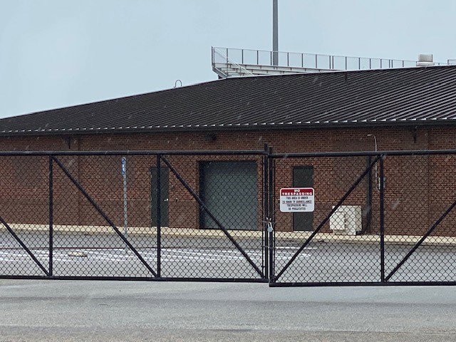 A large black chain link gate securing a commercial or industrial property, installed by National Fence Services, LLC in Macon, GA.