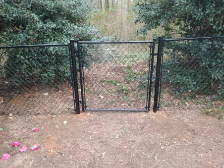 A newly installed black chain-link gate within a fence by Almaraz & Sons LLC in Macon, GA.