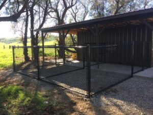 A black chain-link kennel or animal enclosure installed under a shelter by Horizon Fence & Custom Gates, Inc. in Orangevale, CA.