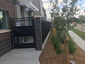 A secure black chain-link fence enclosing a children's playground area next to a building, installed by Best Boy's Fencing in Fort Collins, CO.