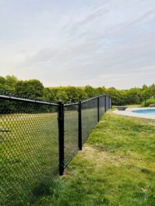A black chain-link fence providing safety around a swimming pool area by Ultra Fence LLC in Brookline, NH.