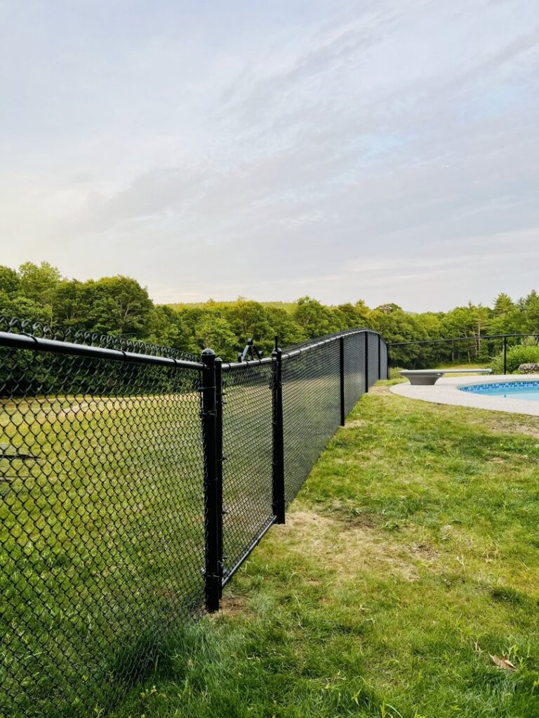 A black chain-link fence providing safety around a swimming pool area by Ultra Fence LLC in Brookline, NH.