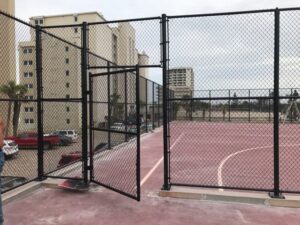 A durable black chain link fence enclosing a sports court, installed by Fencing & Railing 2 Corp in Orlando, FL.
