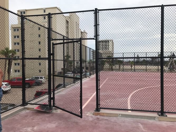 A durable black chain link fence enclosing a sports court, installed by Fencing & Railing 2 Corp in Orlando, FL.