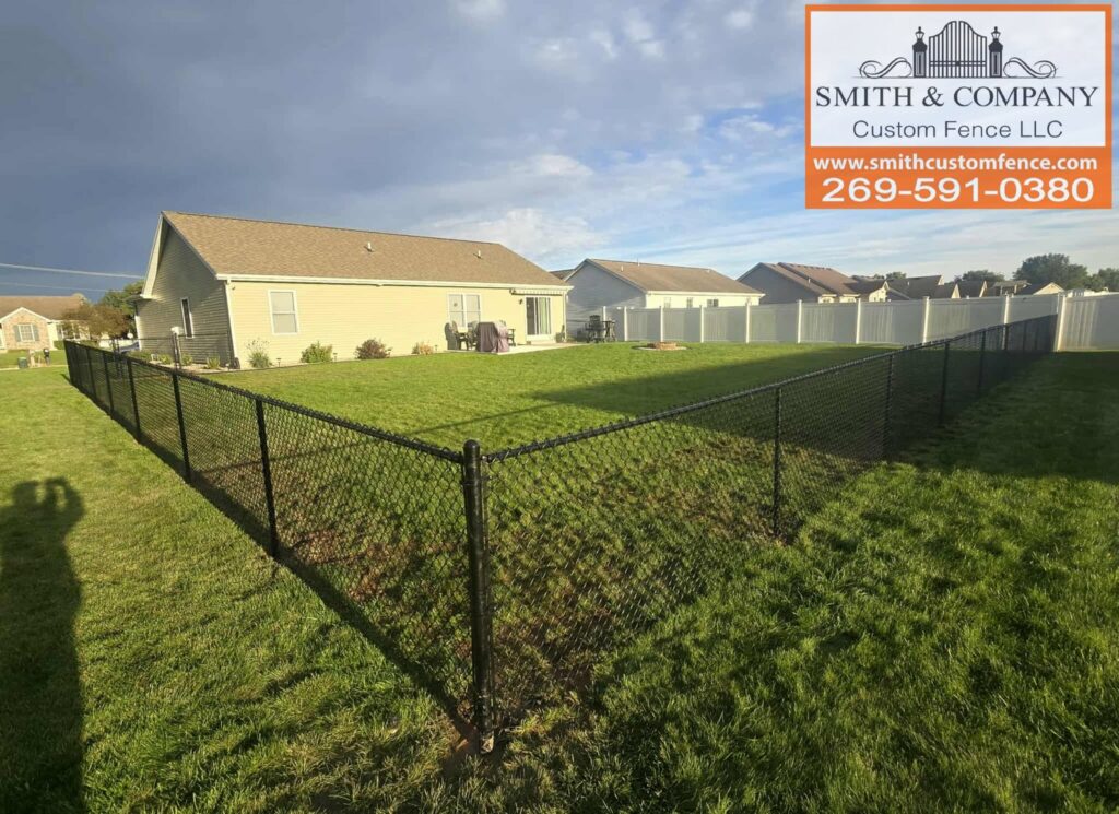 A combination of black chain-link and white vinyl fencing installed in a residential backyard by Smith & Company Custom Fence LLC in Niles, MI.
