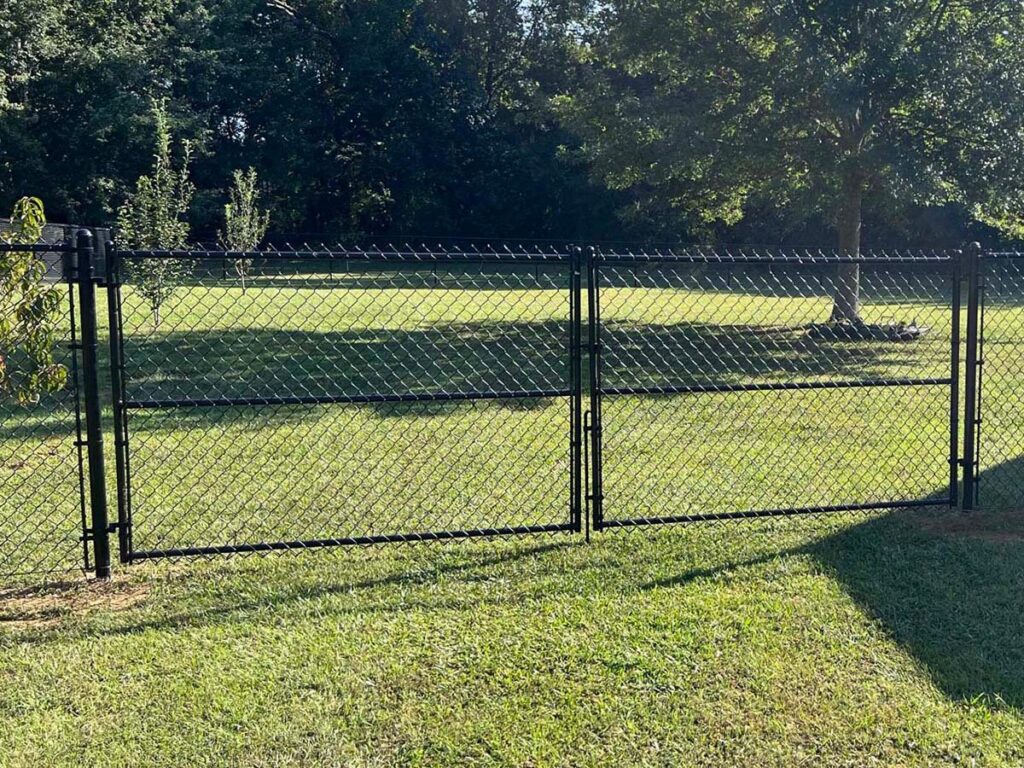 A black chainlink fence with a wide double gate installed in a grassy backyard by RUCO Fence in Huntsville, AL.