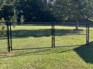 A black chainlink fence with a wide double gate installed in a grassy backyard by RUCO Fence in Huntsville, AL.