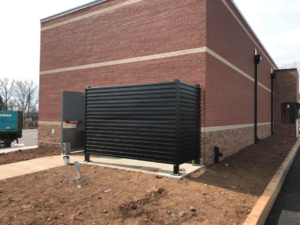A black corrugated metal enclosure installed next to a brick building by Keith's Fence Co LLC in Edison, NJ.