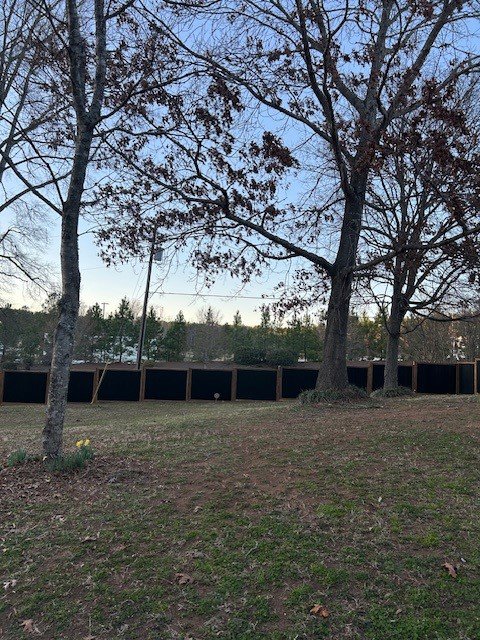 A modern black corrugated metal fence providing privacy in a backyard, installed by Cavitt Fencing in Concord, NC.