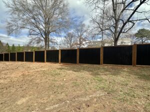 A modern black corrugated metal privacy fence with wooden posts, expertly installed by Cavitt Fencing in Concord, NC.