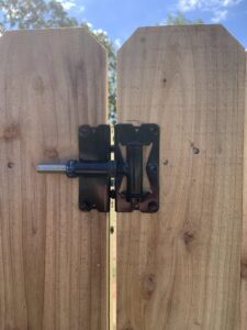 A close-up of a durable black fence gate latch installed on a wooden fence by Superior Fence & Rail of Arkansas in Springdale, AR.