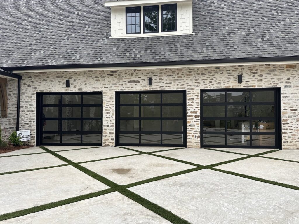 Three black full-view glass garage doors installed on a stone house by Platinum Garage Door Services in Helena, AL