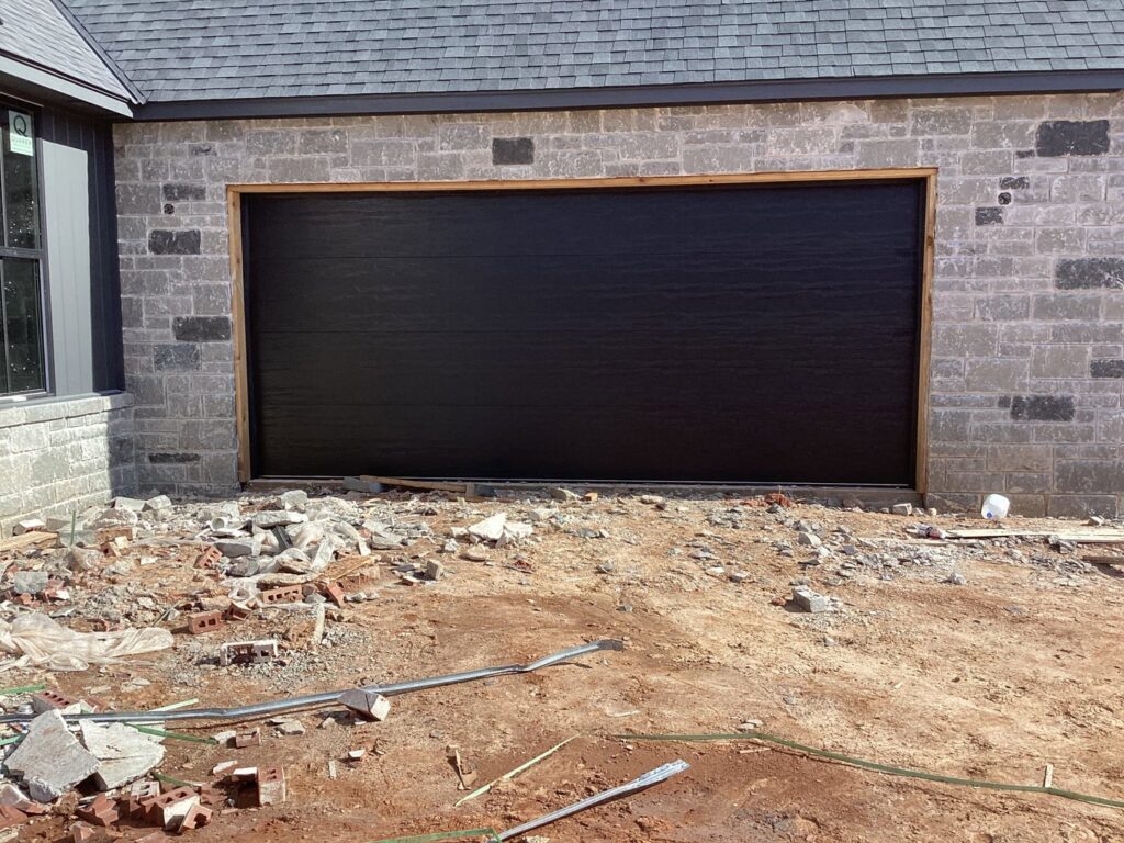 A black garage door installed on a new construction home by CCM Overhead Doors in Oklahoma City, OK
