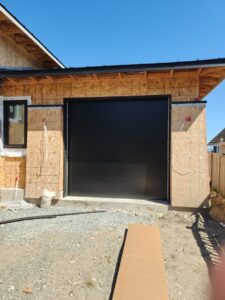A black garage door installed on a new construction home by Overhead Door Company of Everett, Inc in Everett, WA.