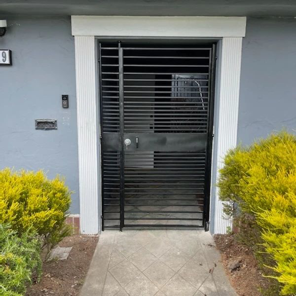 A black metal security gate with horizontal bars at the main entrance, installed by Fierro Iron Works Inc. in San Francisco, CA.