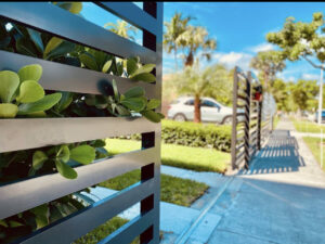 A black horizontal slat fence with a gate installed in a residential area by Miami Fence Installation Contractors in Miami, FL.
