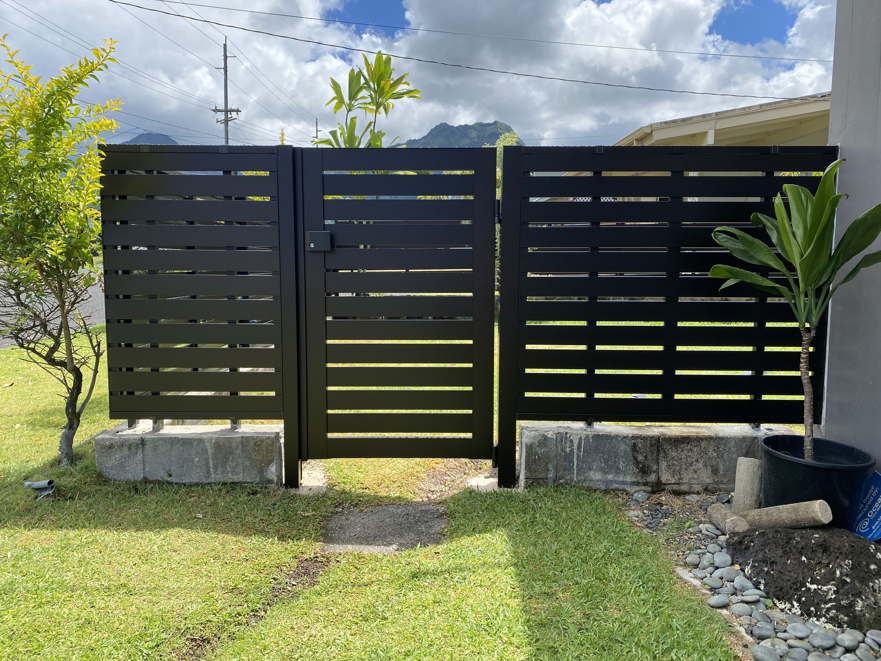 A newly installed black horizontal slat gate with a pedestrian entrance by KunkelWorks Hawaii in Mililani, HI.