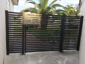 A modern black horizontal slat privacy gate with a keypad entry system by ARE FENCE LLC in Miami, FL.