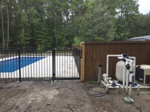 A black ornamental iron fence around a pool with a wooden privacy fence behind it by JB FENCE Brothers company llc in North Charleston, SC.