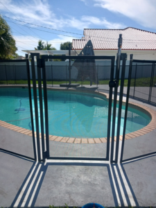 A black mesh pool fence with a self-closing gate installed by All Brand Pool Fence in Fort Lauderdale, FL.